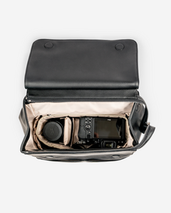 black stylish camera bag backpack black birds eye view, camera body and lens inside padded lining