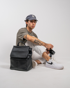 male photographer holds camera and wears black stylish camera bag backpack black front view
